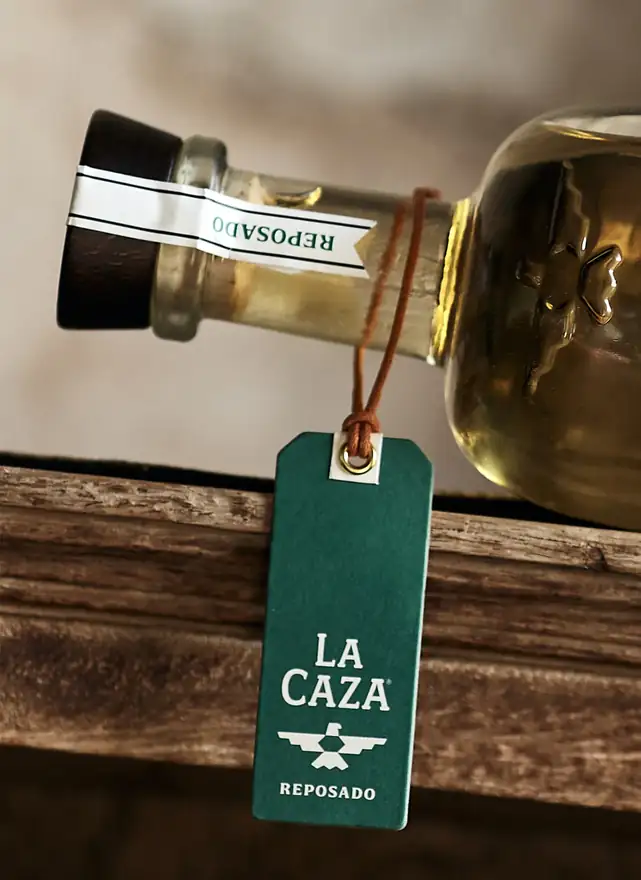 The green La Caza Reposado neck tag tied with leather cord